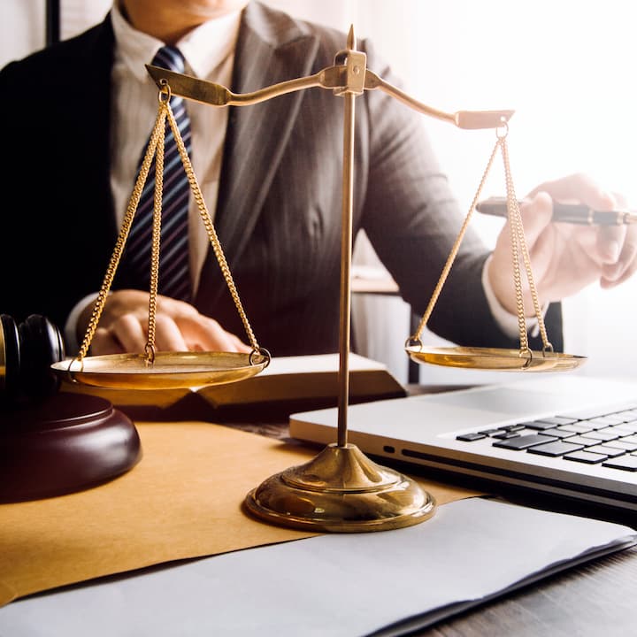 A legal professional working on a laptop with scales on their desk | Services provided for Legal Professionals